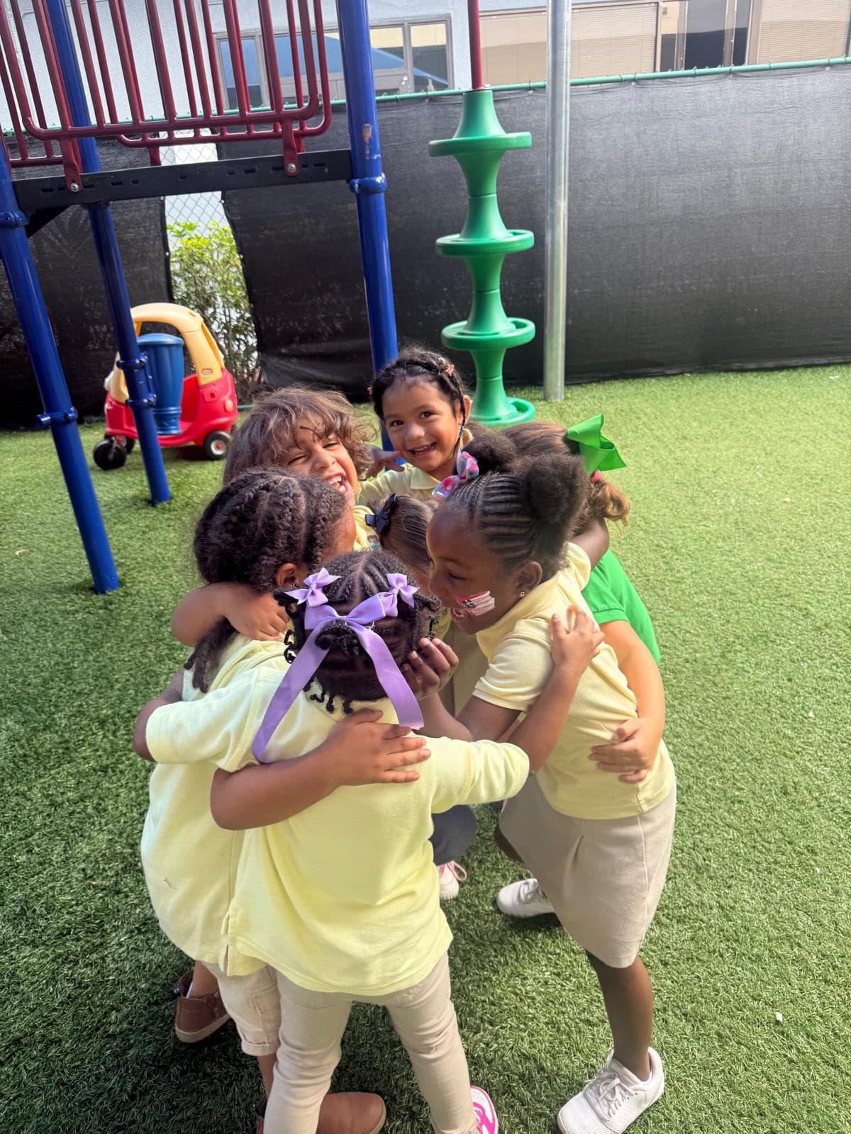 Several children hugging together in a group embrace on an outdoor playground